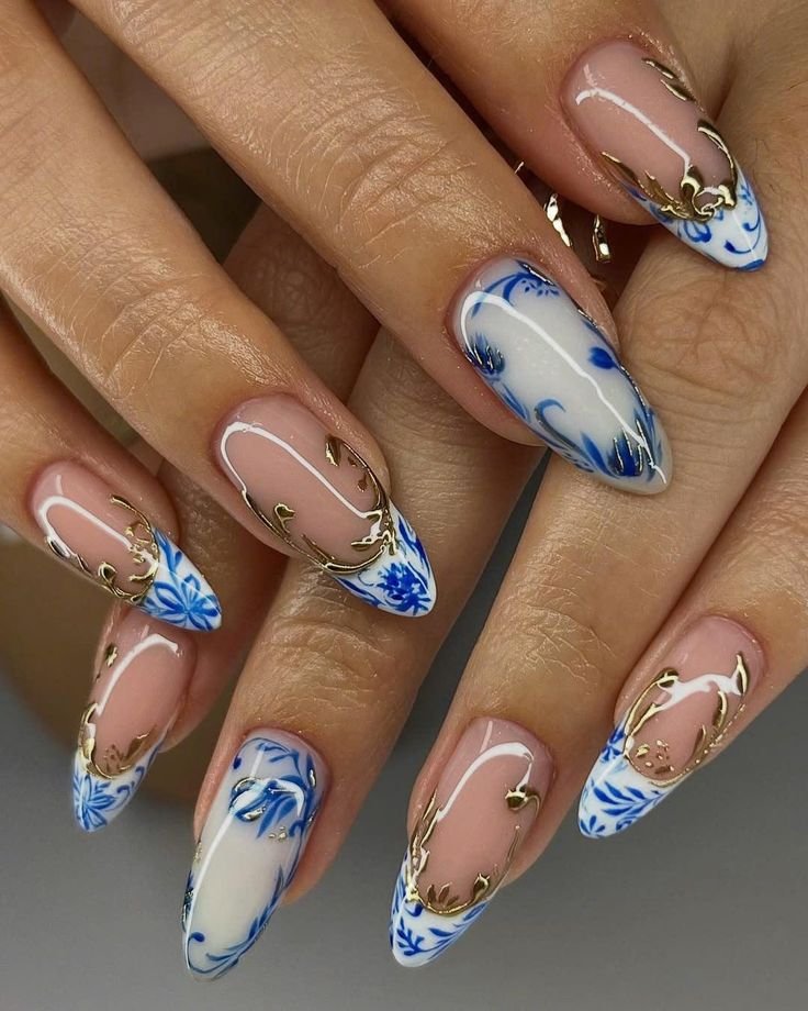 Chinoiserie Blue Porcelain Inspired Nails Ceramic Blue and White Floral Press-on Nails Gold Foil Elegant Nail Art for Special Occasions Elegant blue and gold nail art on almond-shaped nails with intricate floral designs, showcasing stylish manicure trends. - Handy Home Elegant blue and gold nail art on almond-shaped nails with intricate floral designs, showcasing stylish manicure trends.