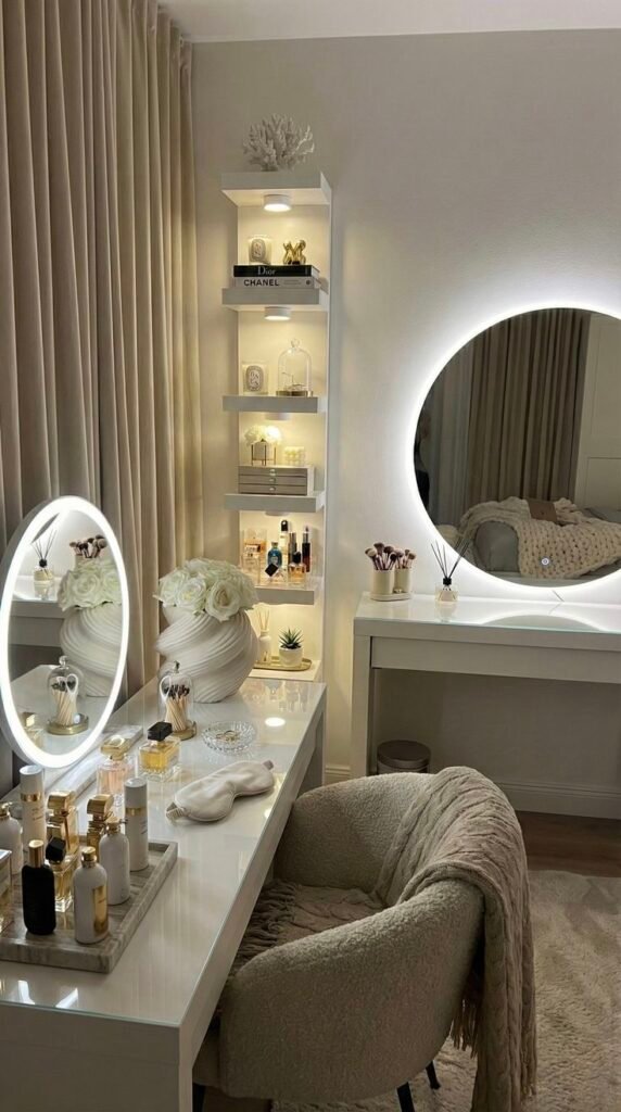 Elegant vanity with illuminated mirror, perfumes, and decor; cozy chair and plush throw in chic, organized beauty corner.