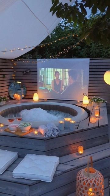 Outdoor hot tub with relaxing movie night setup, cozy candles, snacks, and string lights for a perfect backyard retreat.