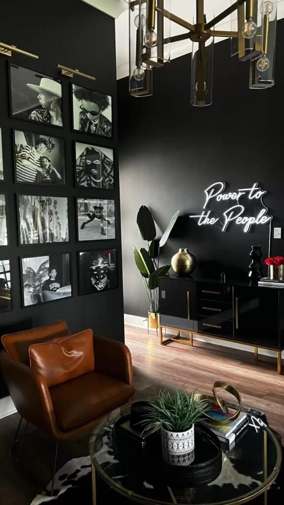 Chic black living room with leather chair, gallery wall, neon sign saying Power to the People, and modern decor accents.