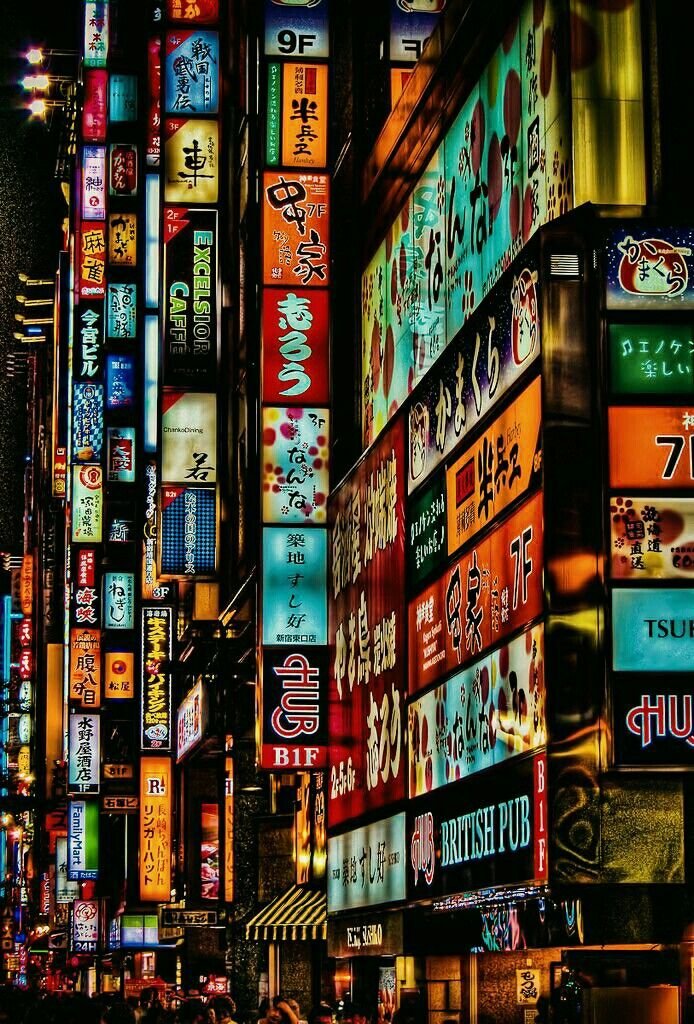 Colorful neon signs illuminate a bustling street in Japan, showcasing vibrant nightlife and urban energy.
