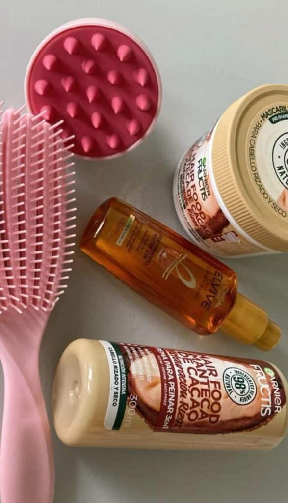 Hair rutine 🎀 Pink scalp massager, hairbrush, and hair products including oil, cream, and mask for curly hair care on a marble surface. - Handy Home Pink scalp massager, hairbrush, and hair products including oil, cream, and mask for curly hair care on a marble surface.