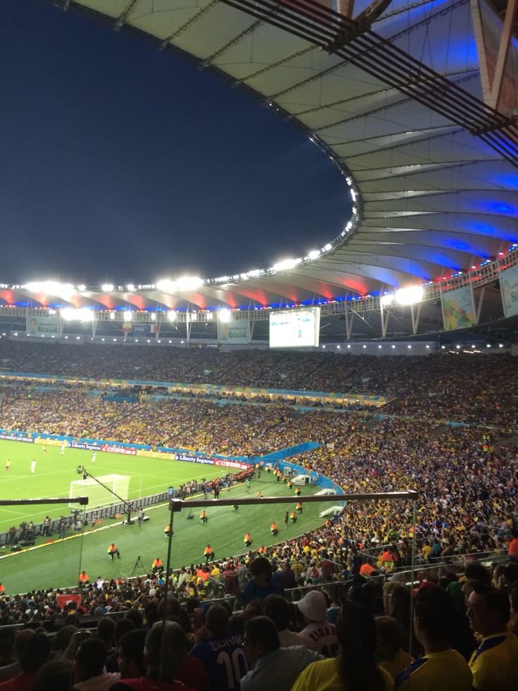 Stadium packed with fans at a vibrant night football match, colorful lights and cheering crowd creating an electrifying atmosphere.