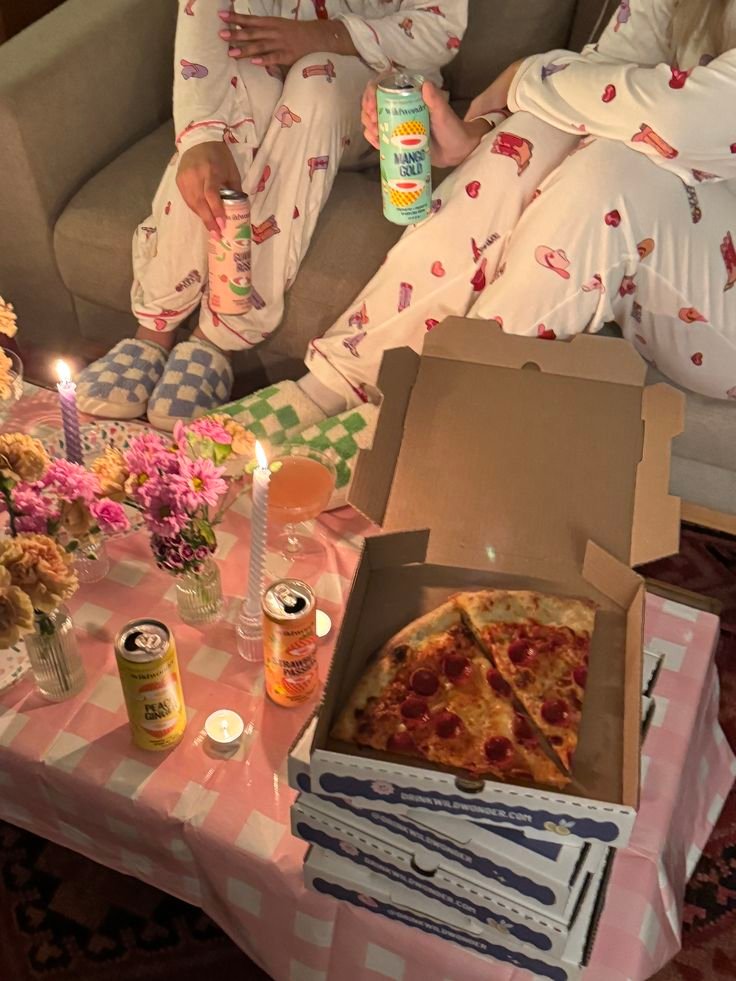 Pizza night in Cozy pizza night with friends in pajamas, enjoying drinks, candles, and flowers on a table with a checkered cloth. - Handy Home Cozy pizza night with friends in pajamas, enjoying drinks, candles, and flowers on a table with a checkered cloth.