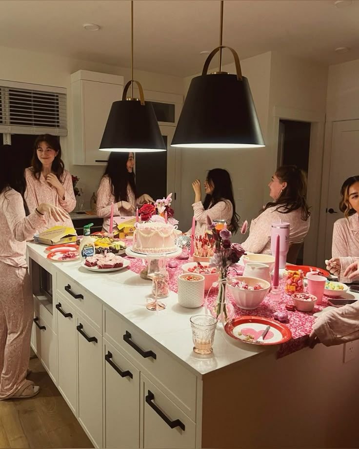 SPRING SLEEPOVER_ HOW TO HOST THE PERFECT SLUMBER PARTY Women in pink pajamas enjoying a cozy indoor party with cake and snacks on a decorated kitchen island. - Handy Home Women in pink pajamas enjoying a cozy indoor party with cake and snacks on a decorated kitchen island.
