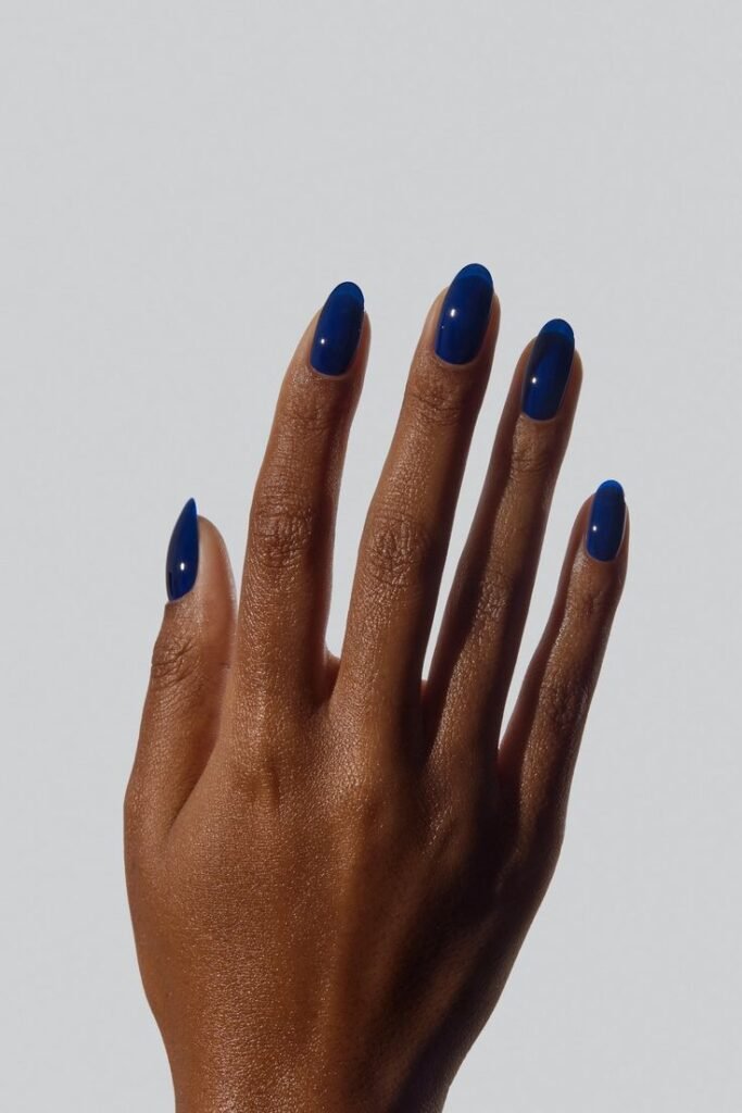 Sapphire Hand with glossy blue nails against a neutral background, showcasing a stylish and bold manicure design. Perfect for nail art inspiration. - Handy Home Hand with glossy blue nails against a neutral background, showcasing a stylish and bold manicure design. Perfect for nail art inspiration.
