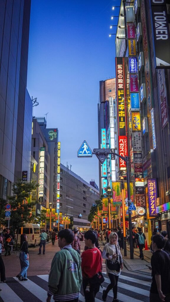 Bustling Tokyo street at dusk, vibrant neon signs and people crossing. Urban nightlife in Japan.