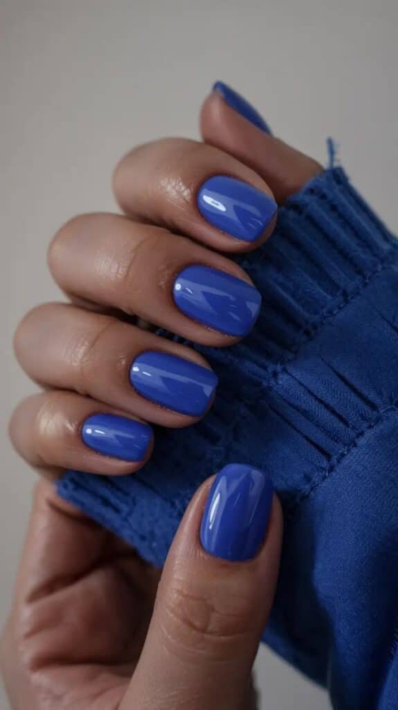 Short Nails 2026_ Electric Blue Energy Boost Bright blue manicured nails and matching sweater create a stylish, coordinated look for nail art and fashion enthusiasts. - Handy Home Bright blue manicured nails and matching sweater create a stylish, coordinated look for nail art and fashion enthusiasts.