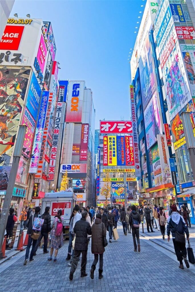 Bustling Akihabara street, Tokyo with colorful billboards, shops, and crowds showcasing vibrant city life and electronic stores.