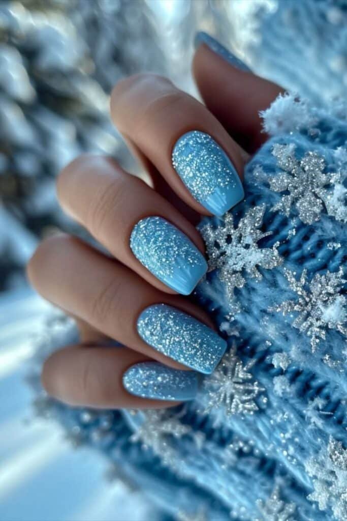Winter Ice Blue Nails 2024_ Icy Palette 💅❄️ Sparkling blue snowflake nail design on a hand in a cozy winter sweater, perfect for festive nail inspiration. - Handy Home Sparkling blue snowflake nail design on a hand in a cozy winter sweater, perfect for festive nail inspiration.