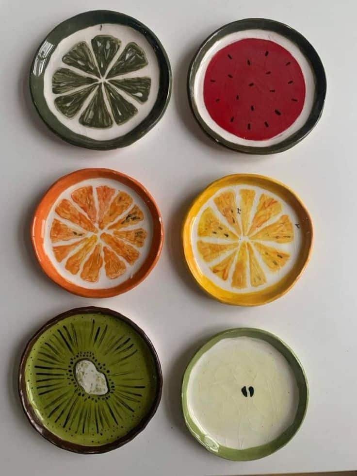 Colorful fruit-themed ceramic coasters, including designs of lemon, orange, kiwi, lime, and watermelon, arranged on a white surface.