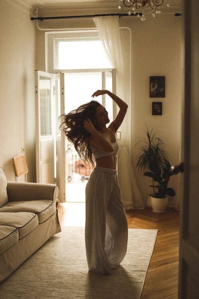 bad0a357-20bb-43c4-bec0-a570f550af60 Woman dancing joyfully at home in cozy sunlight, wearing comfortable loungewear. Relaxed and happy indoor atmosphere. - Handy Home Woman dancing joyfully at home in cozy sunlight, wearing comfortable loungewear. Relaxed and happy indoor atmosphere.