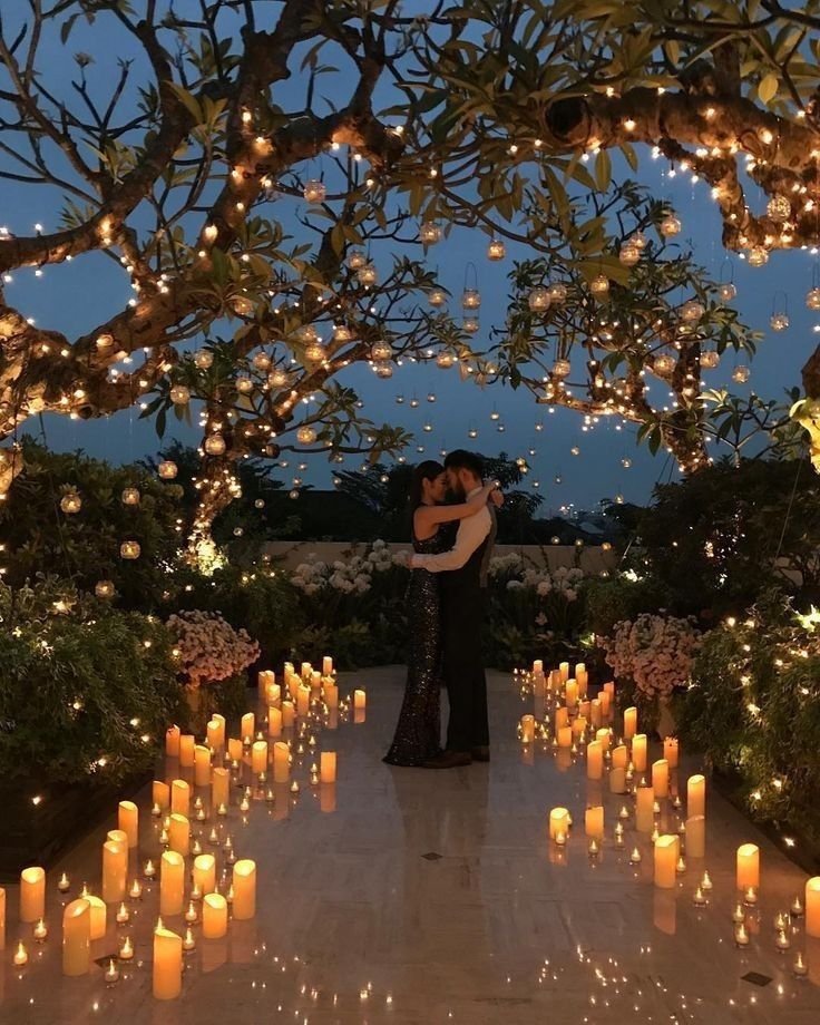 Romantic candlelit evening dance under twinkling lights and archway in a lush garden setting. Perfect for wedding inspiration.