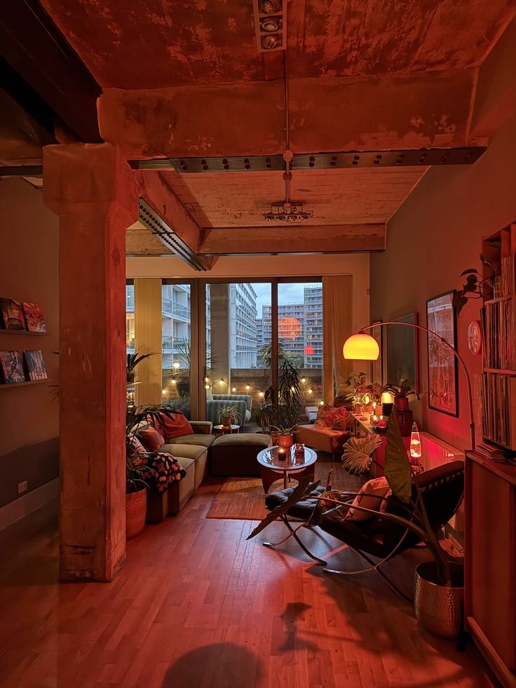 Cozy urban loft with ambient lighting, mid-century decor, and large windows showcasing a city view. Warm, inviting atmosphere.