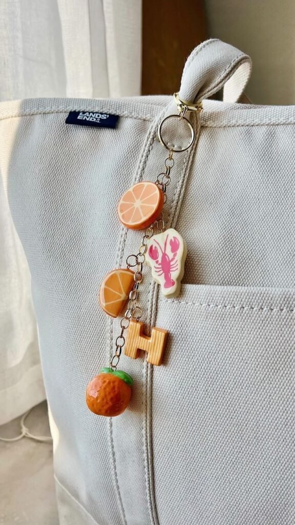 Canvas bag with fruit and lobster-themed keychain, including citrus slices and an orange, attached to the handle.