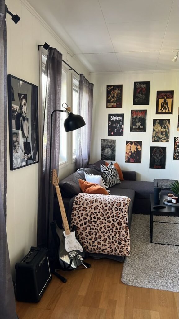 Cozy music-themed room with guitar, posters, and cozy couch with animal print blanket, lamp softly lighting the corner. Grunge Apartment Aesthetic