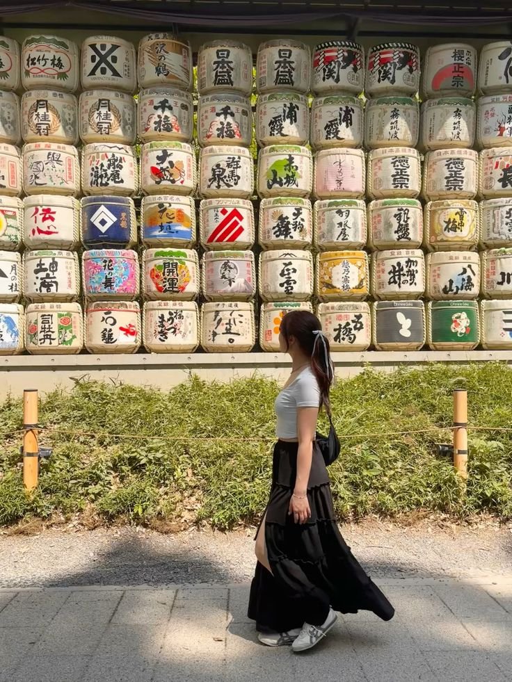 Woman walking past colorful Japanese sake barrels at shrine, Tokyo. Traditions and culture in harmony.