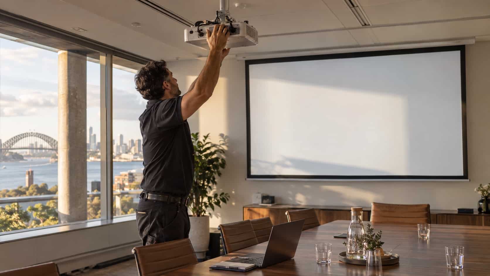 Plan Your Display Setup With Projector Hire Sydney A technician aligning a projector and screen in a bright Sydney meeting venue, crisp blank projected surface with no text - Handy Home A technician aligning a projector and screen in a bright Sydney meeting venue, crisp blank projected surface with no text