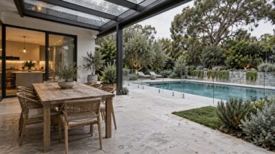 Modern outdoor living area with a glass patio roof and frameless pool fence